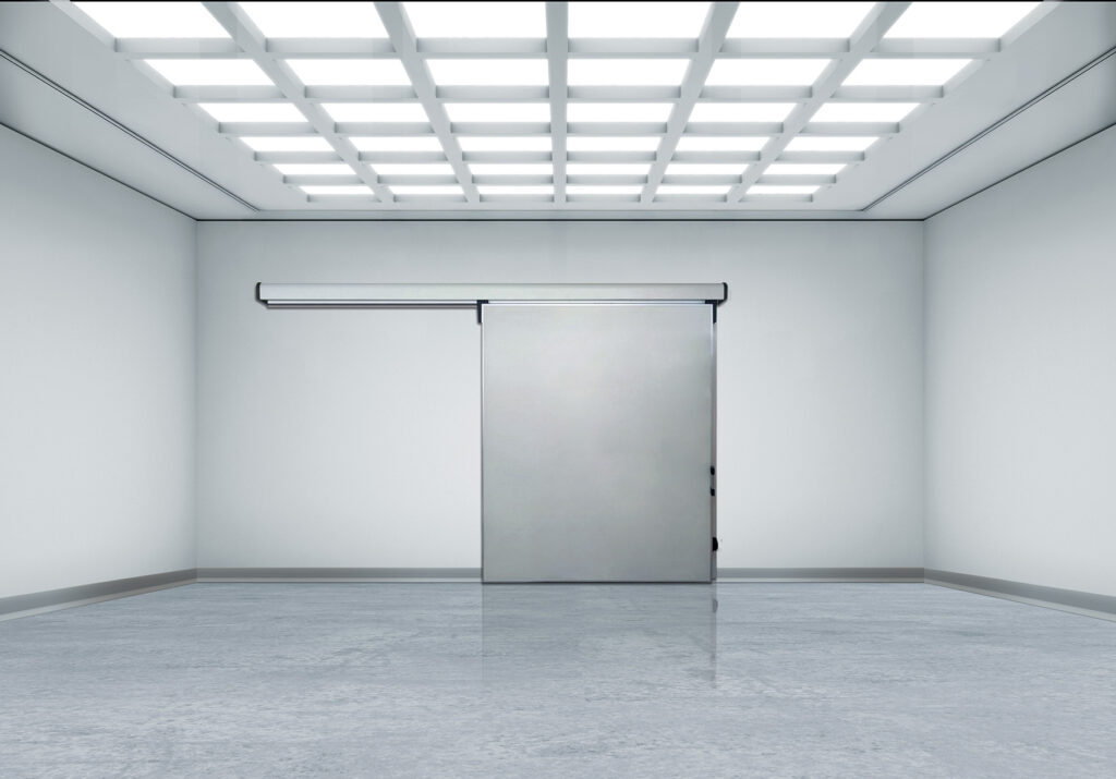 Sterile room with bright grid ceiling and stainless sliding door.
