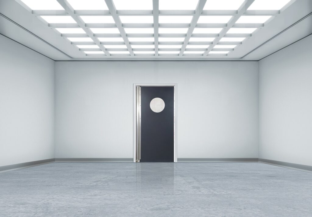 Minimalist white room with grid lights and a black door with circular window.