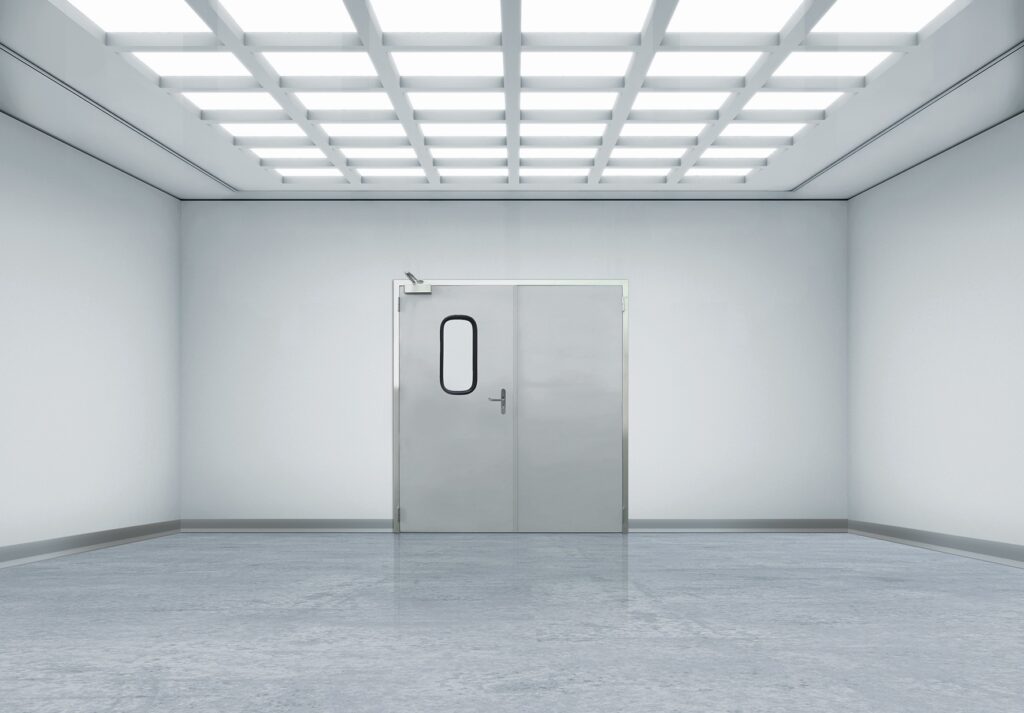 Sterile white room with stainless steel double doors and grid ceiling lights.