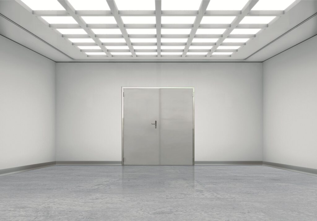 Empty sterile room with grid ceiling lights, metal double doors, and polished floor.
