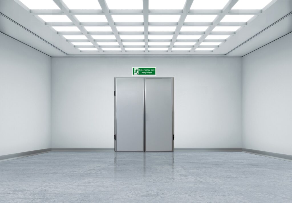 Empty white hallway with double doors under emergency exit sign - nooddeuren