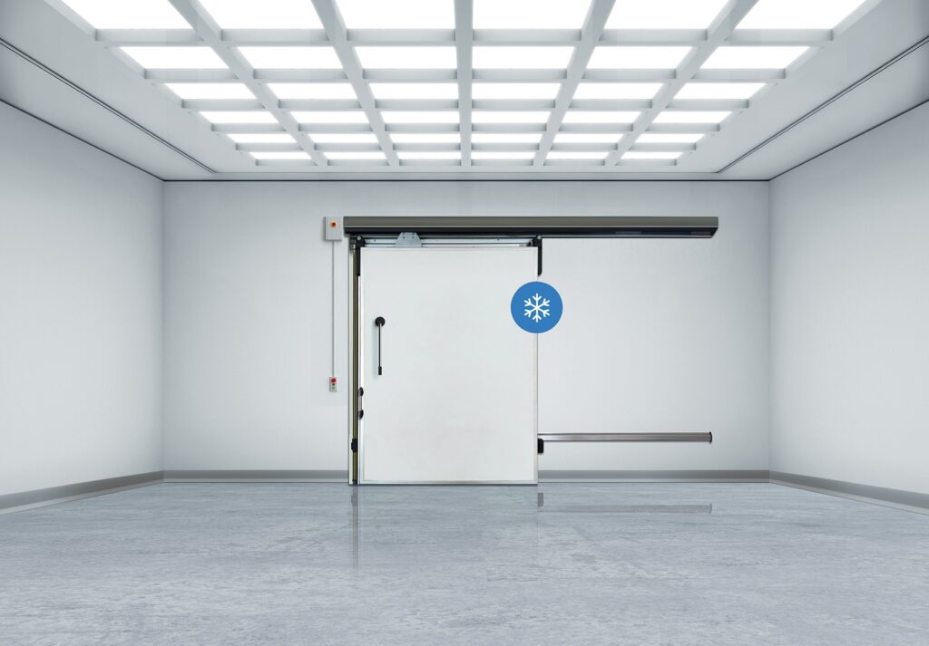 Empty sterile room with a sliding freezer door under grid lights.