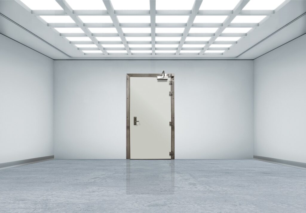 Minimalist white room with polished floor and a reinforced metal door under grid ceiling lights.