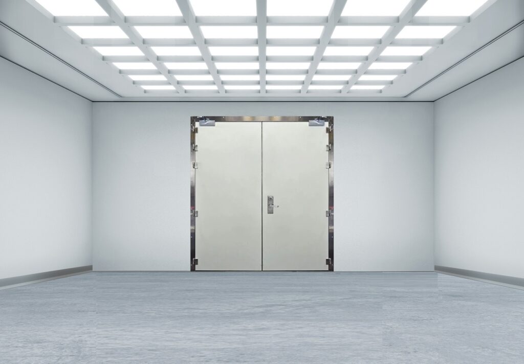 Empty white industrial room with double metal doors beneath grid ceiling lights